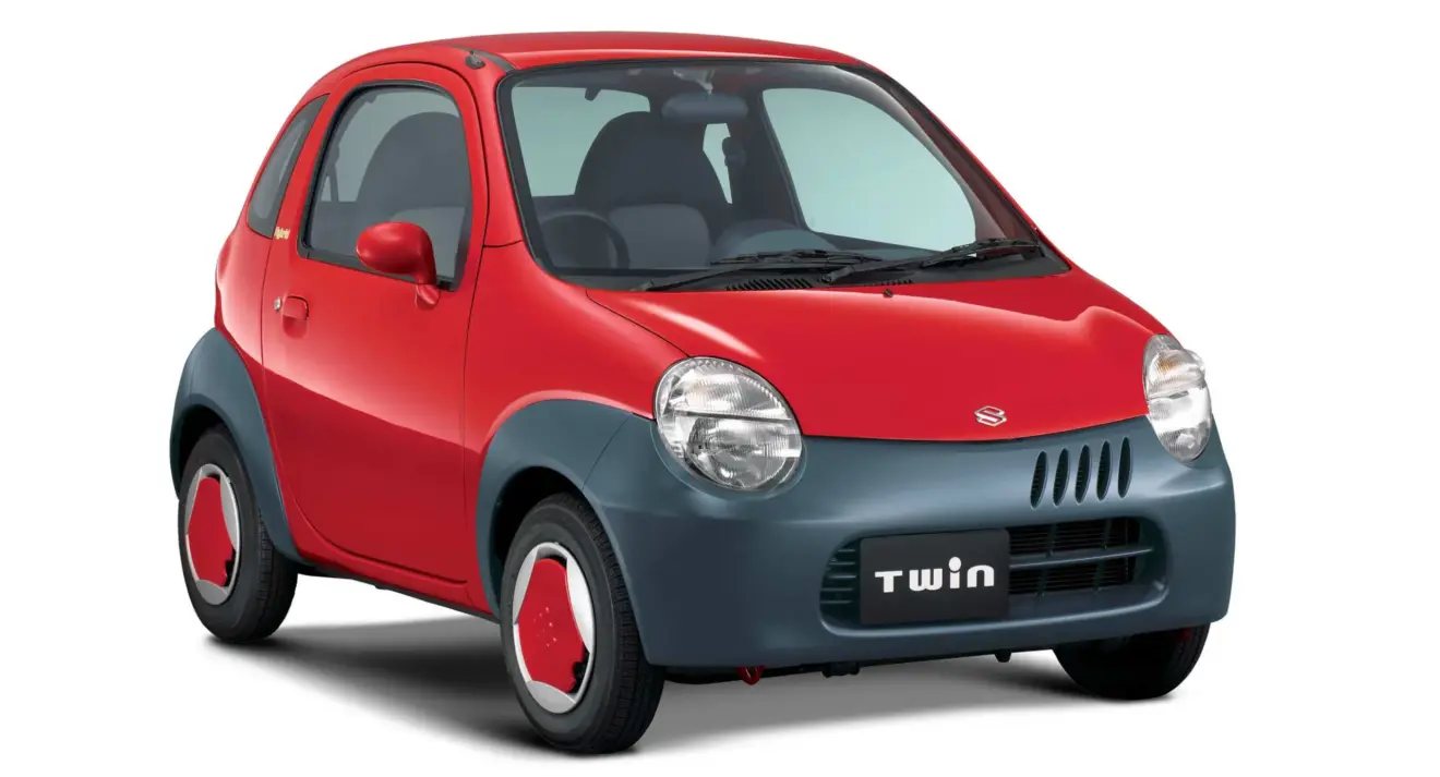 Suzuki Twin vermelho parado de frente com fundo branco é um carro que parece de brinquedo