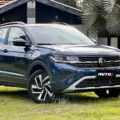 Volkswagen T-Cross Comfortline azul de frente em um gramado com uma casa ao fundo