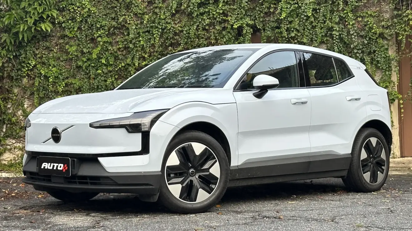 Volvo Ex30 Core branco parado de frente com muro e plantas ao fundo