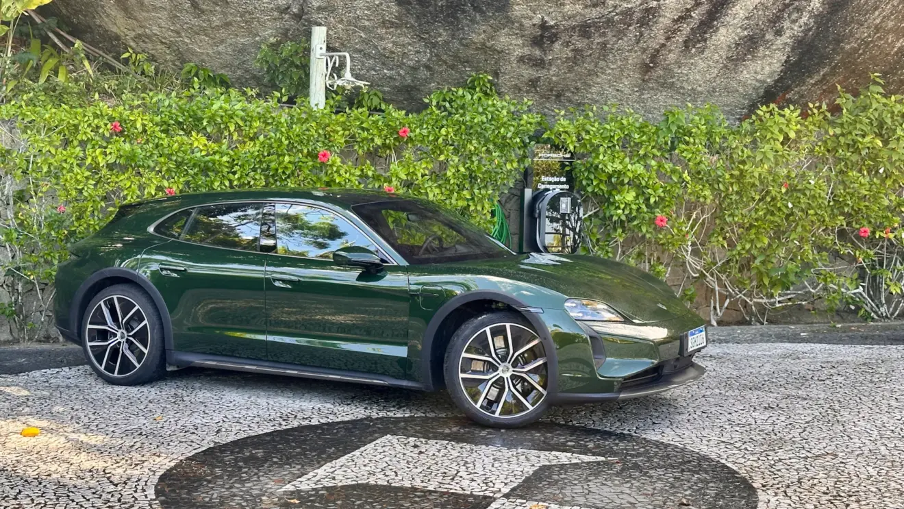 Porsche Taycan Cross Turismo Turbo verde de lado em um jardim com um carregador da Porsche ao lado