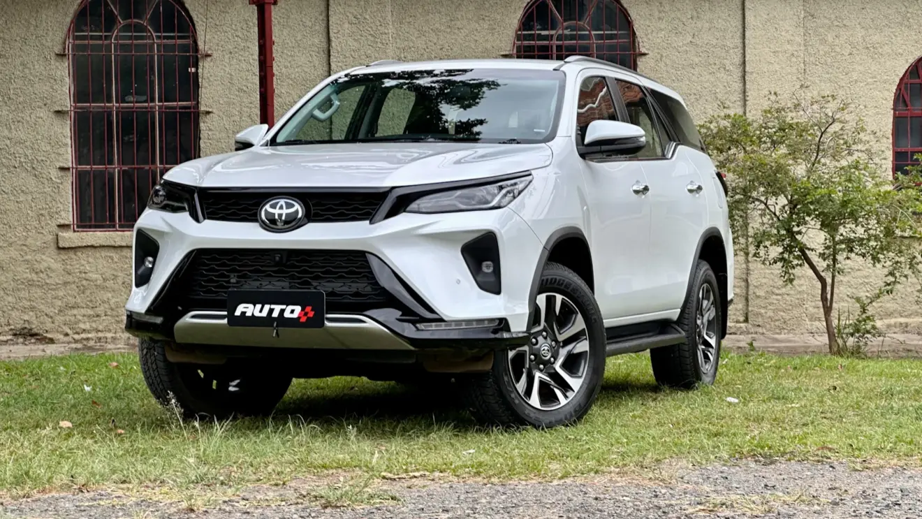 Toyota SW4 SRX Platinum 7 lugares branco de lado com uma casa antiga e um gramado ao fundo carros