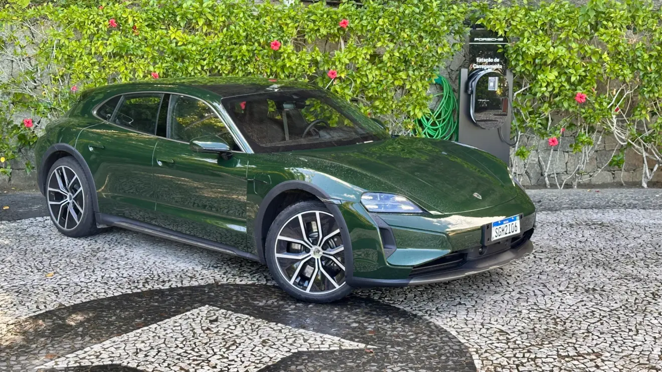 Porsche Taycan Cross Turismo Turbo verde de frente em um jardim com um carregador da Porsche ao lado