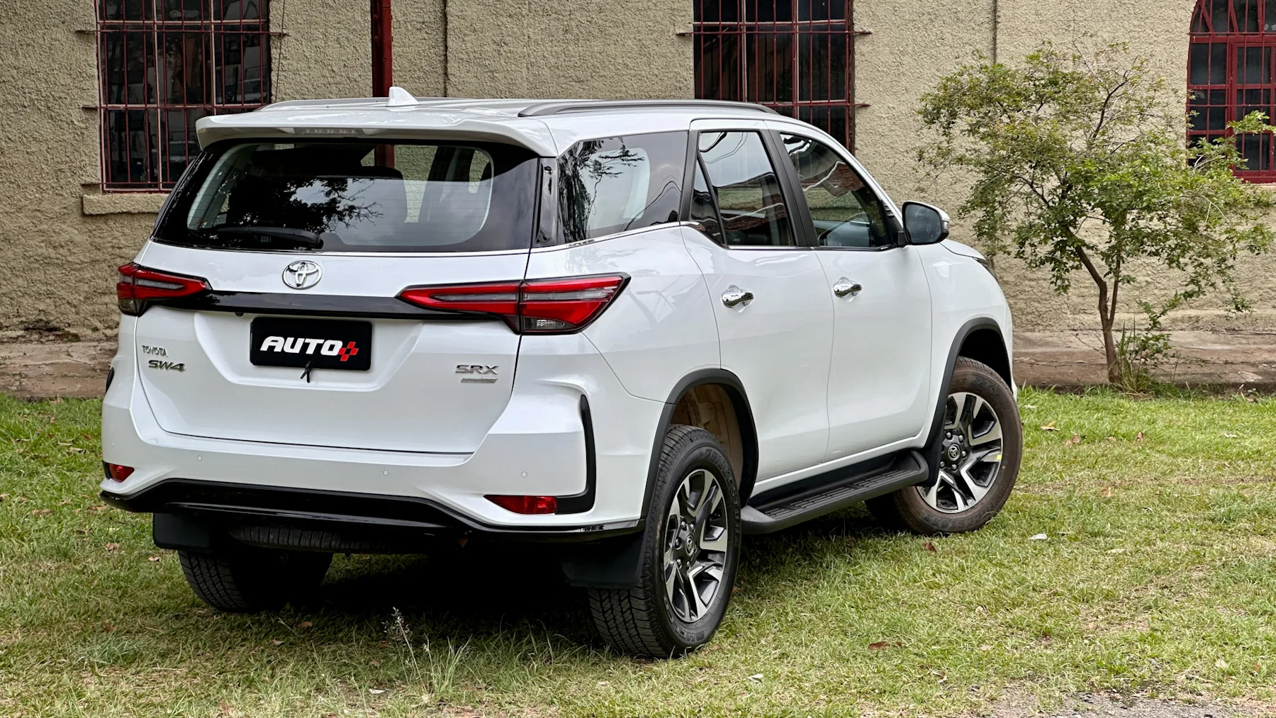 Toyota SW4 SRX Platinum 7 lugares branco de traseira com uma casa antiga e um gramado ao fundo