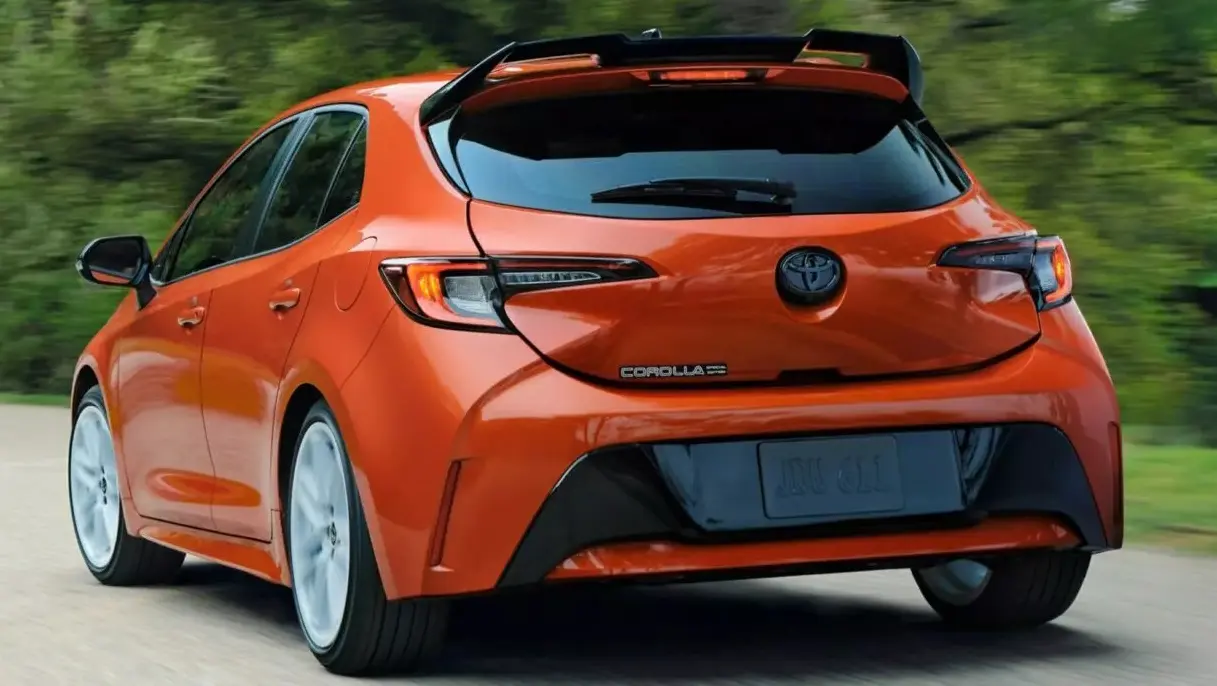 Vista de trás do Toyota Corolla hatch FX Edition 2026 laranja com detalhes pretos e lanternas acesas