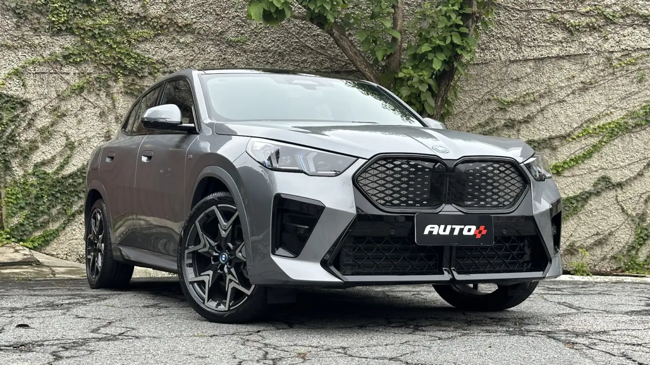 BMW iX2 cinza parado de frente com muro de cimento ao fundo