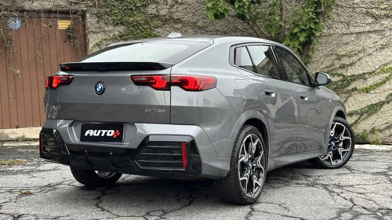 BMW iX2 cinza parado de frente com muro de cimento ao fundo