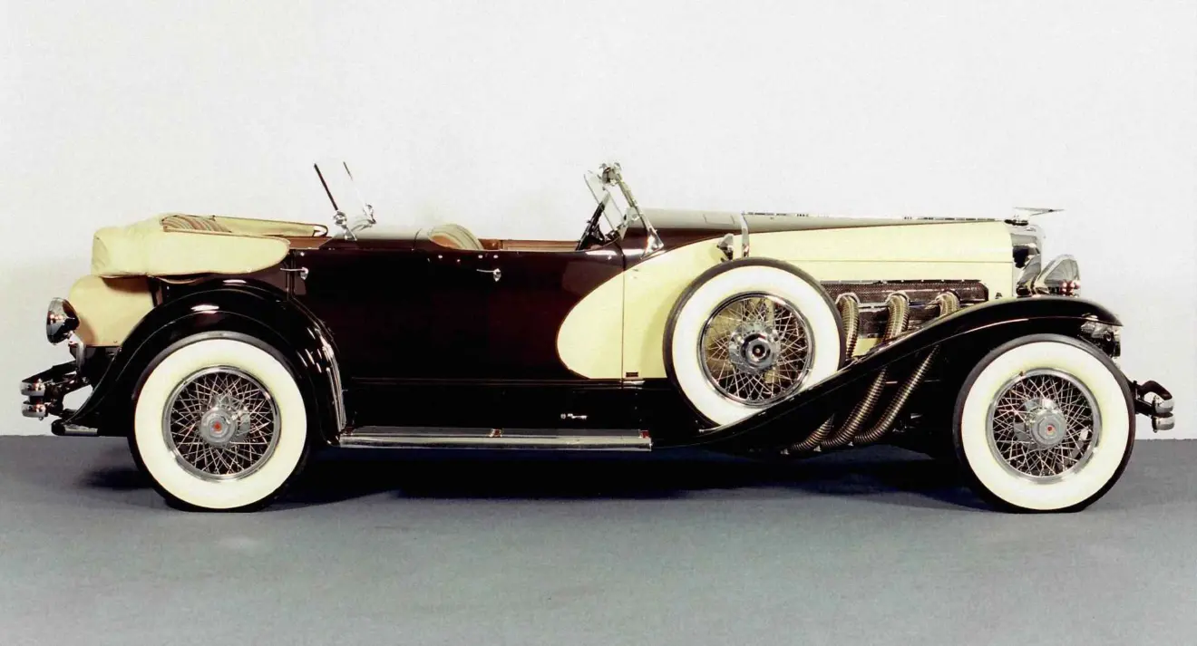 Duessenberg J marrom e creme parado de lateral com fundo branco