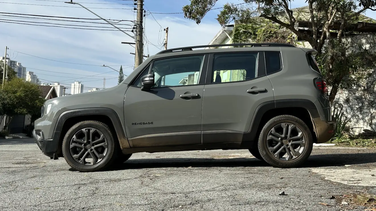 Jeep Renegade Longitude Night Eagle cinza parado de lateral com muro e plantas ao fundo