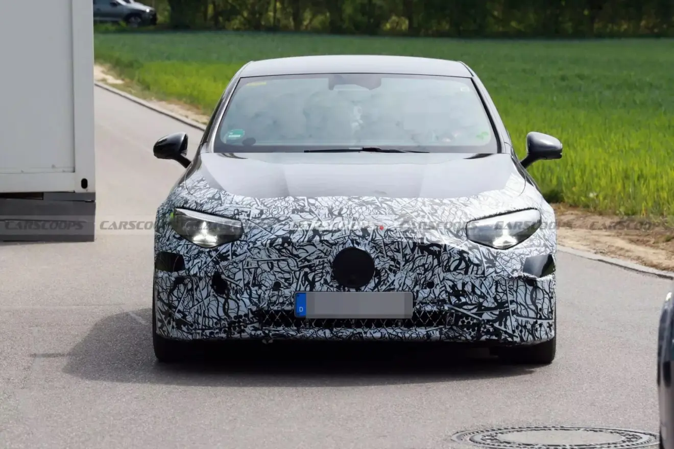 Vista de frente com faróis acesos do Mercedes-AMG CLA elétrico preto camuflado
