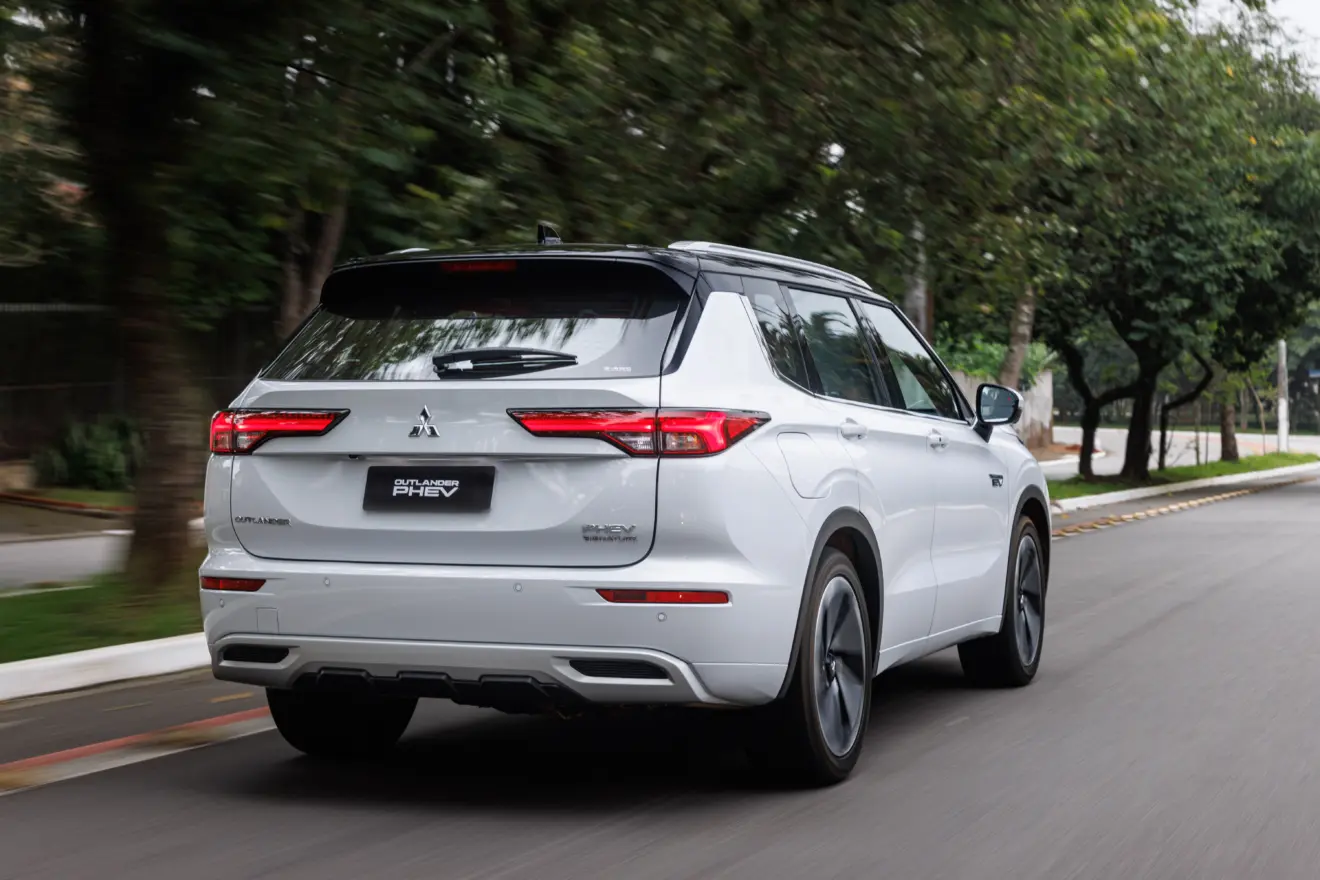 Novo Mitsubishi Outlander PHEV branco parado de traseira andando na cidade 