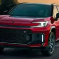 Toyota RAV4 GR-Sport vermelho com detalhes pretos, visto de tfrente e com faróis acesos