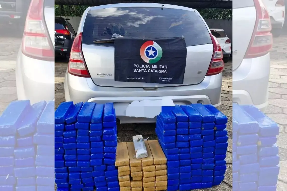 Renault Sandero prata visto de trás e tabletes de maconha apreendidos