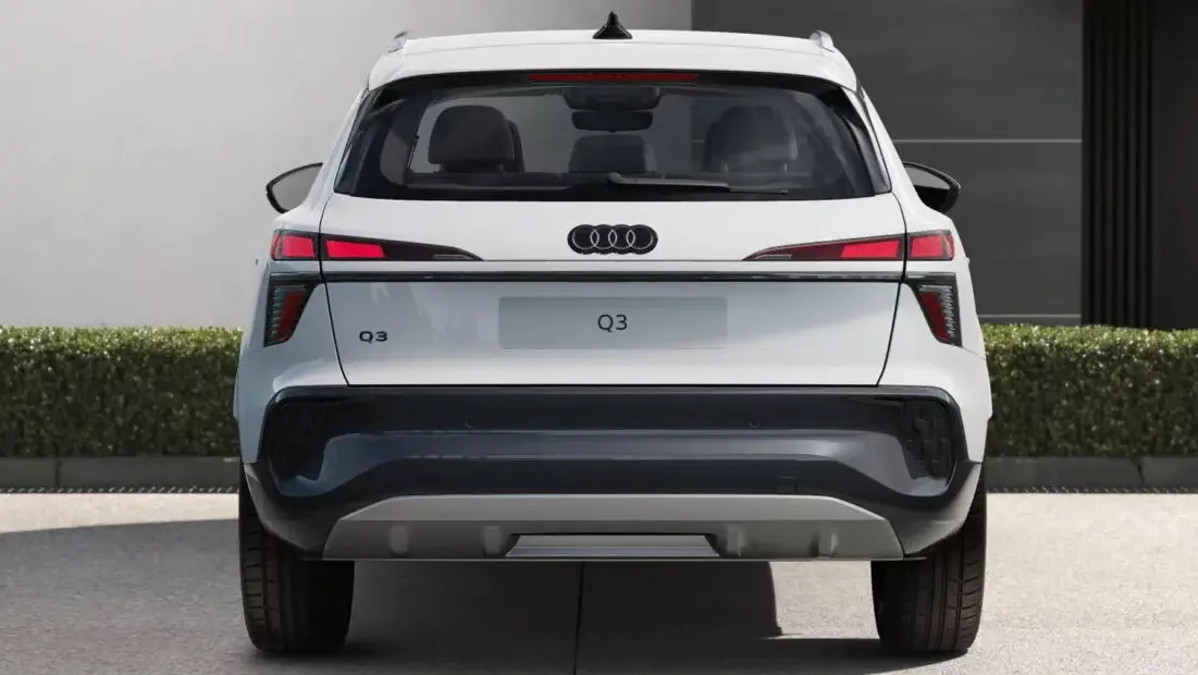 Vista traseira do novo Audi Q3 na versão basis, pintado de branco e com lanternas acesas