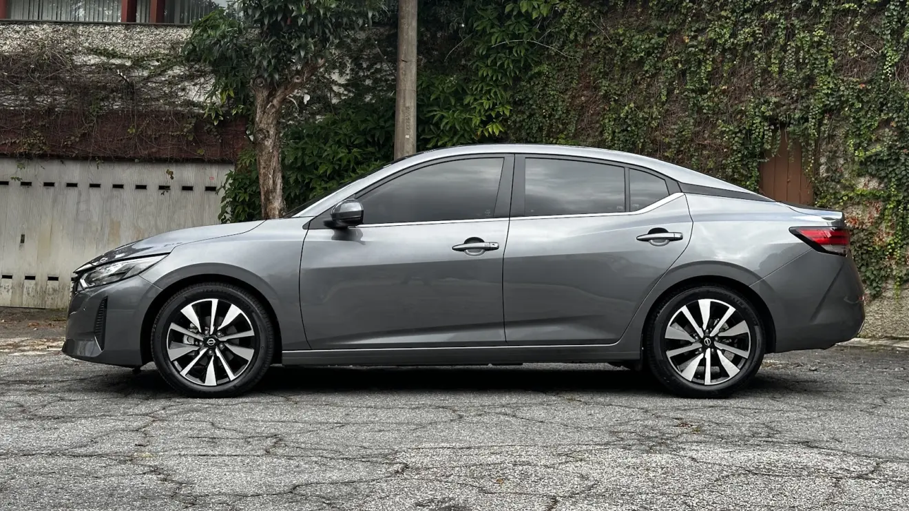 Nissan Sentra Advance cinza parado de lateral com muro e plantas ao fundo