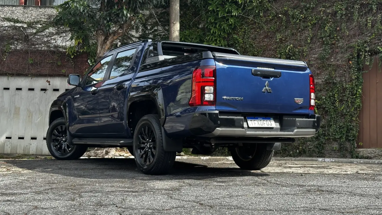 Caminhonete média Mitsubishi Triton Katana azul parada de traseira com muro ao fundo