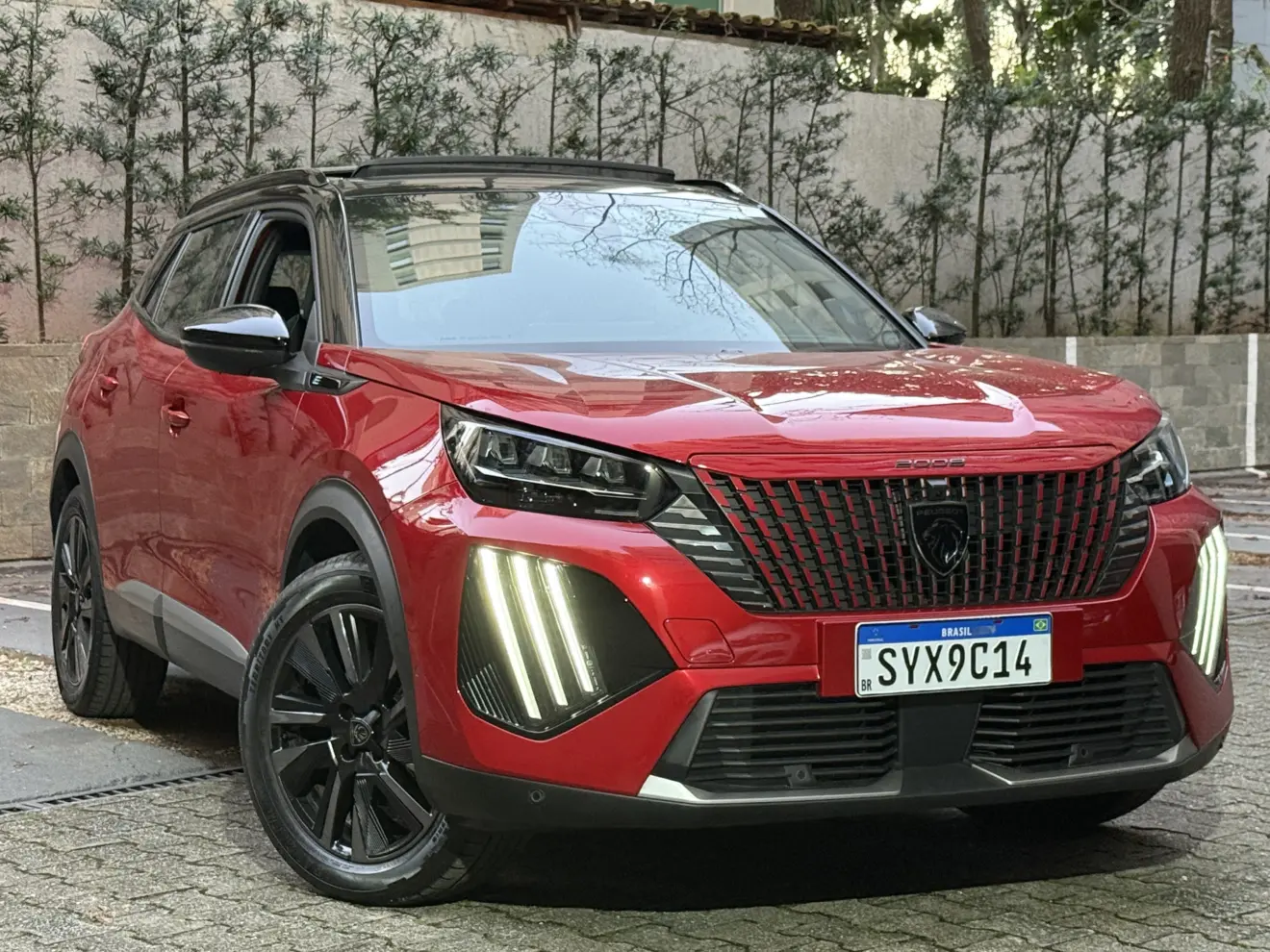 Peugeot e-2008 GT vermelho com partes pretas, DRL's acesos e visto de frente