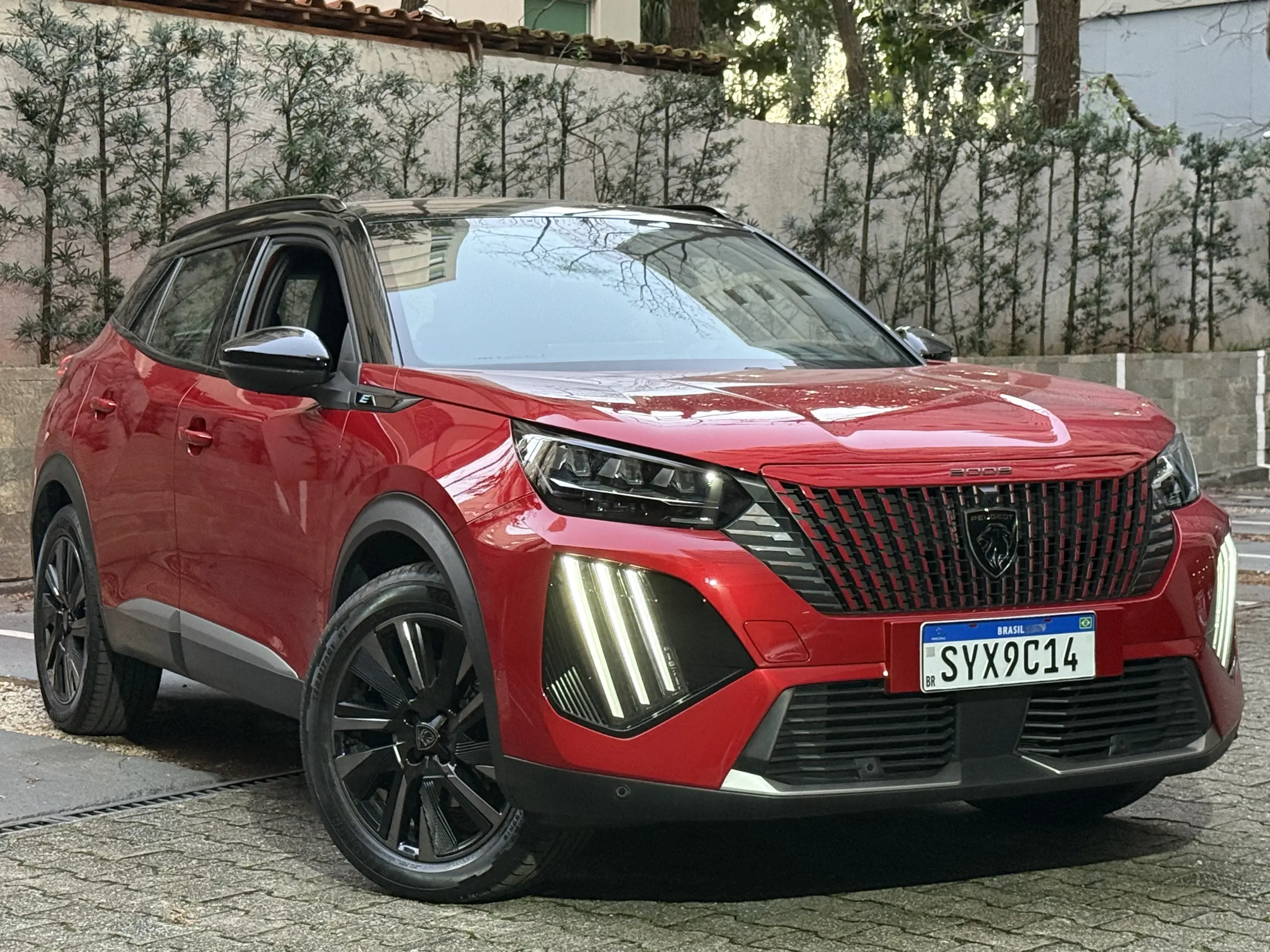 Peugeot e-2008 GT vermelho com partes pretas, DRL's acesos e visto de frente