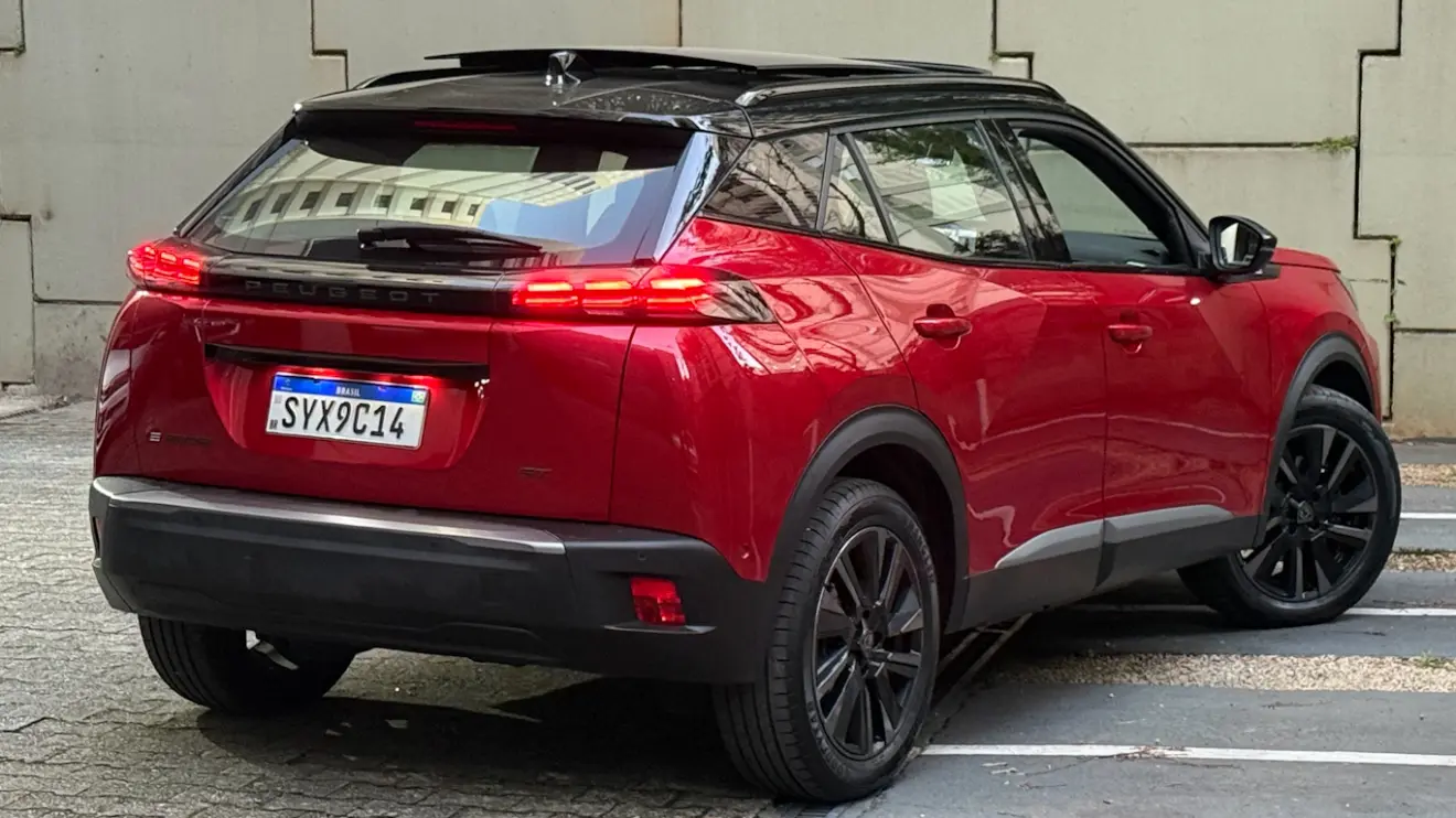 Peugeot e-2008 GT vermelho com partes pretas, visto de trás e com lanternas acesas