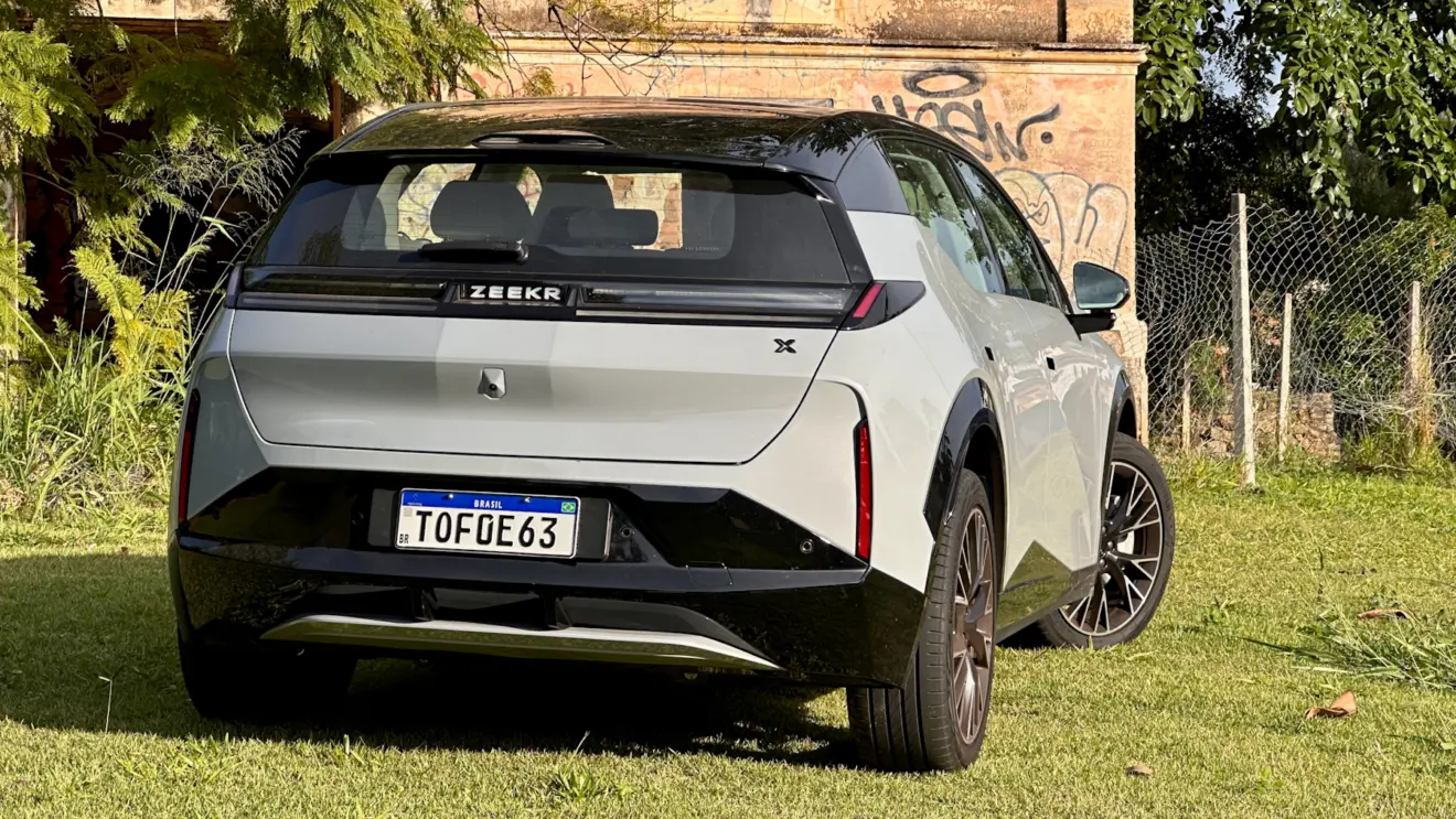 Zeekr X Flagship cinza com teto preto em frente a uma casa abandonada