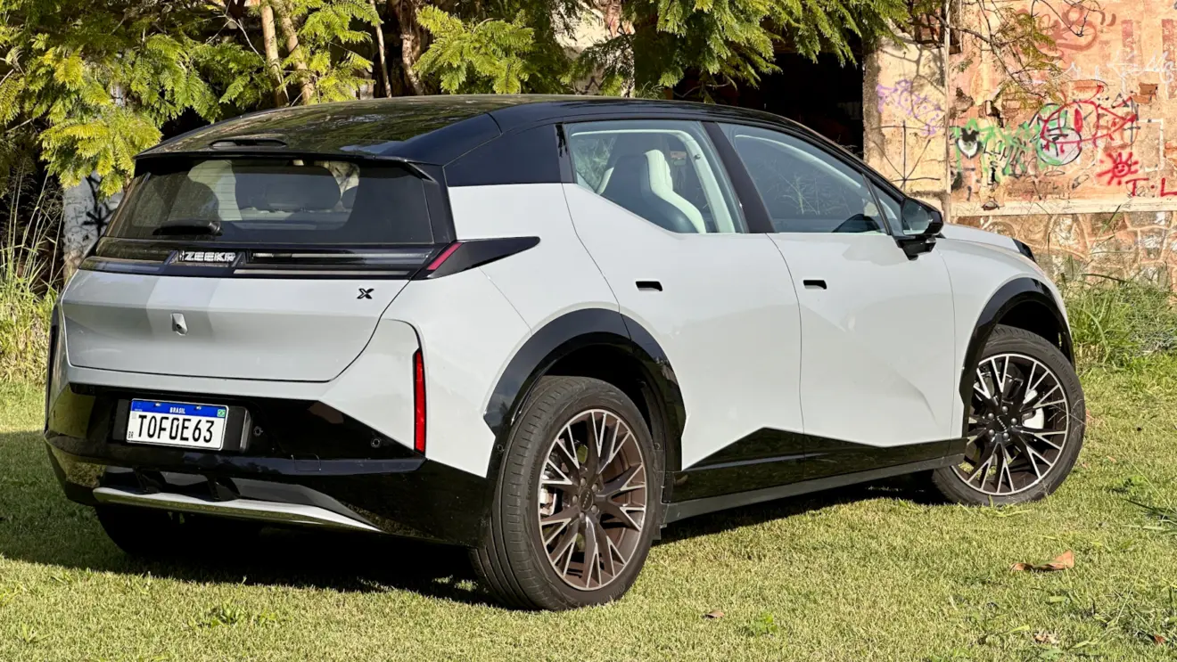 Zeekr X Flagship cinza com teto preto em frente a uma casa abandonada