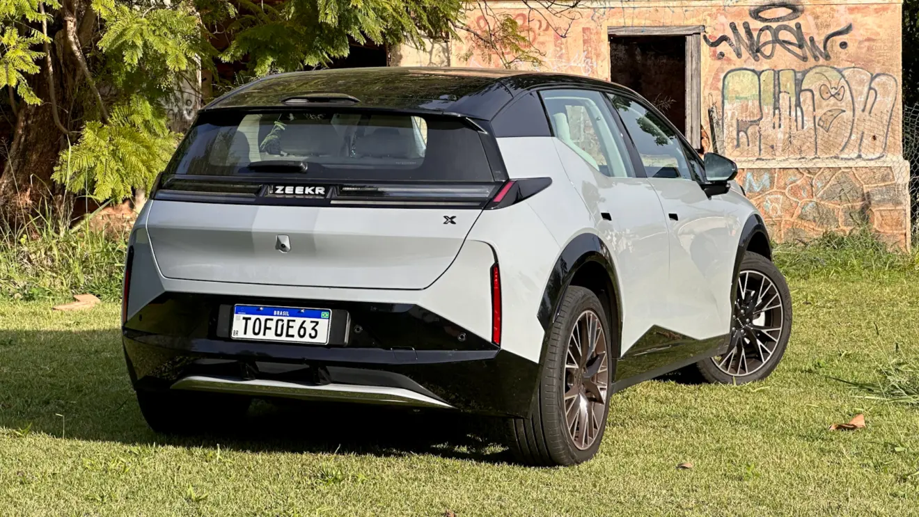 Zeekr X Flagship cinza com teto preto em frente a uma casa abandonada