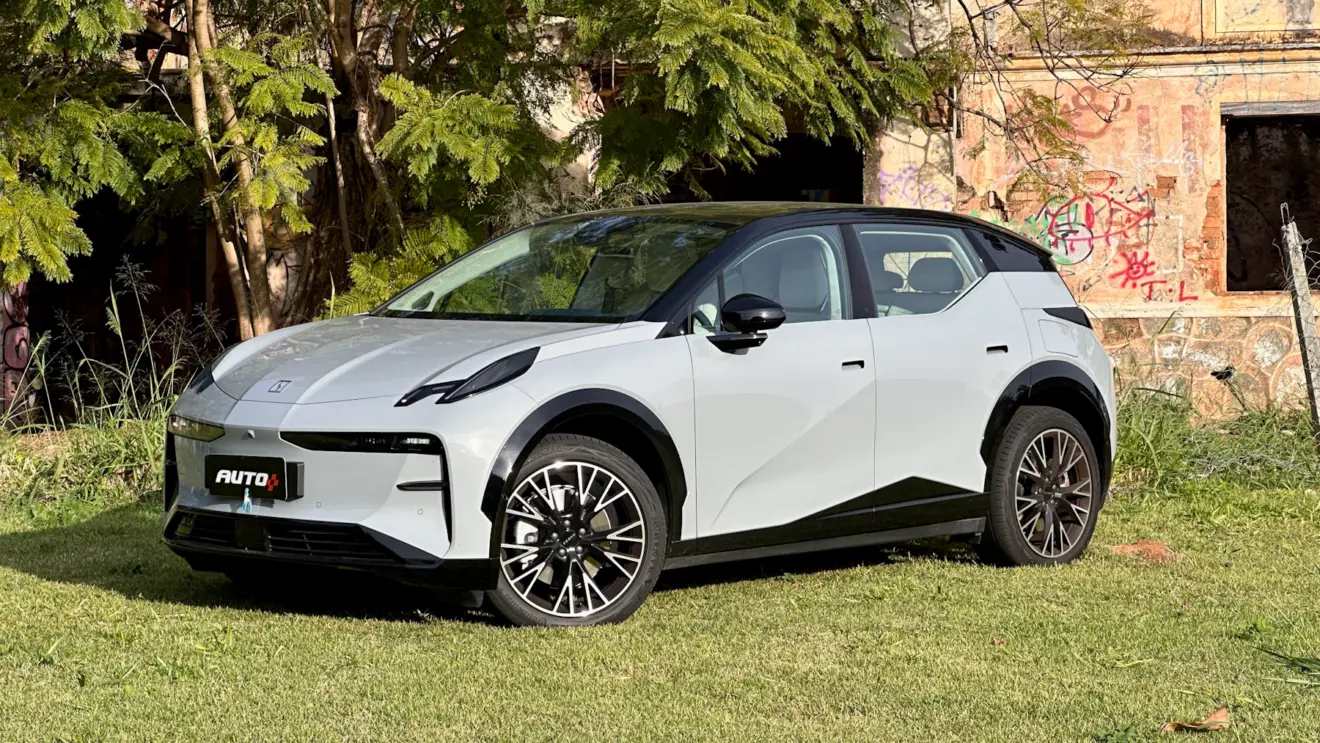 Zeekr X Flagship cinza com teto preto em frente a uma casa abandonada