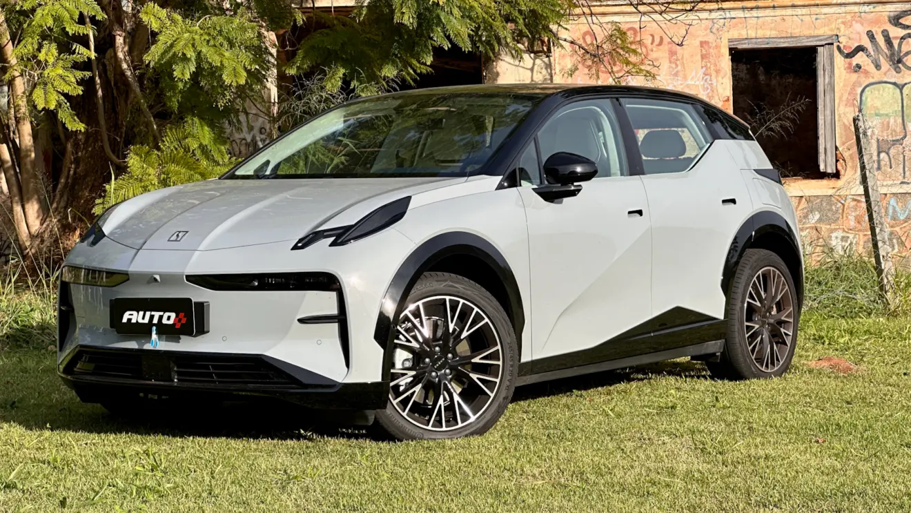 Zeekr X Flagship cinza com teto preto em frente a uma casa abandonada