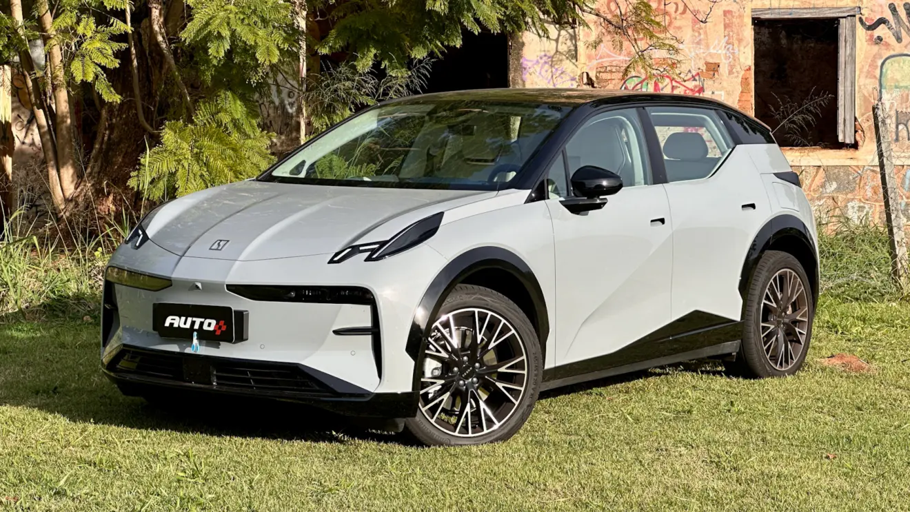 Zeekr X Flagship cinza com teto preto em frente a uma casa abandonada