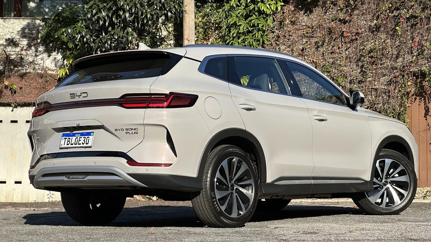 BYD Song Plus 2026 dourado parado de traseira com muro e plantas ao fundo