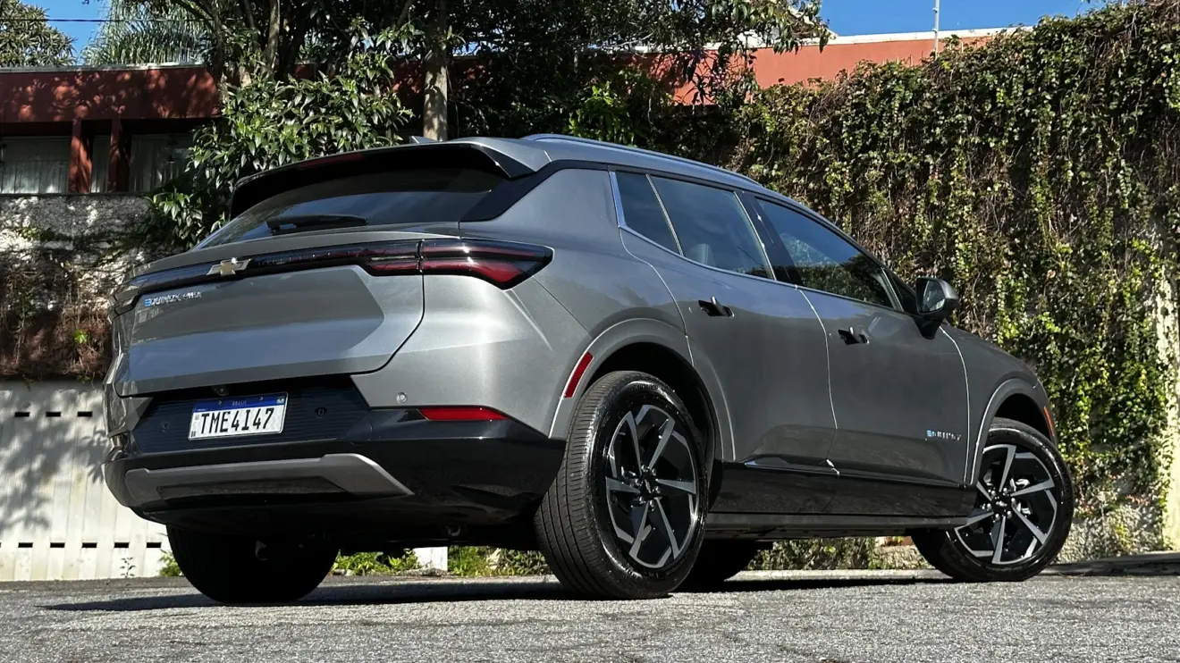 Chevrolet Equinox EV AWD prata parado de traseira com muro e plantas ao fundo