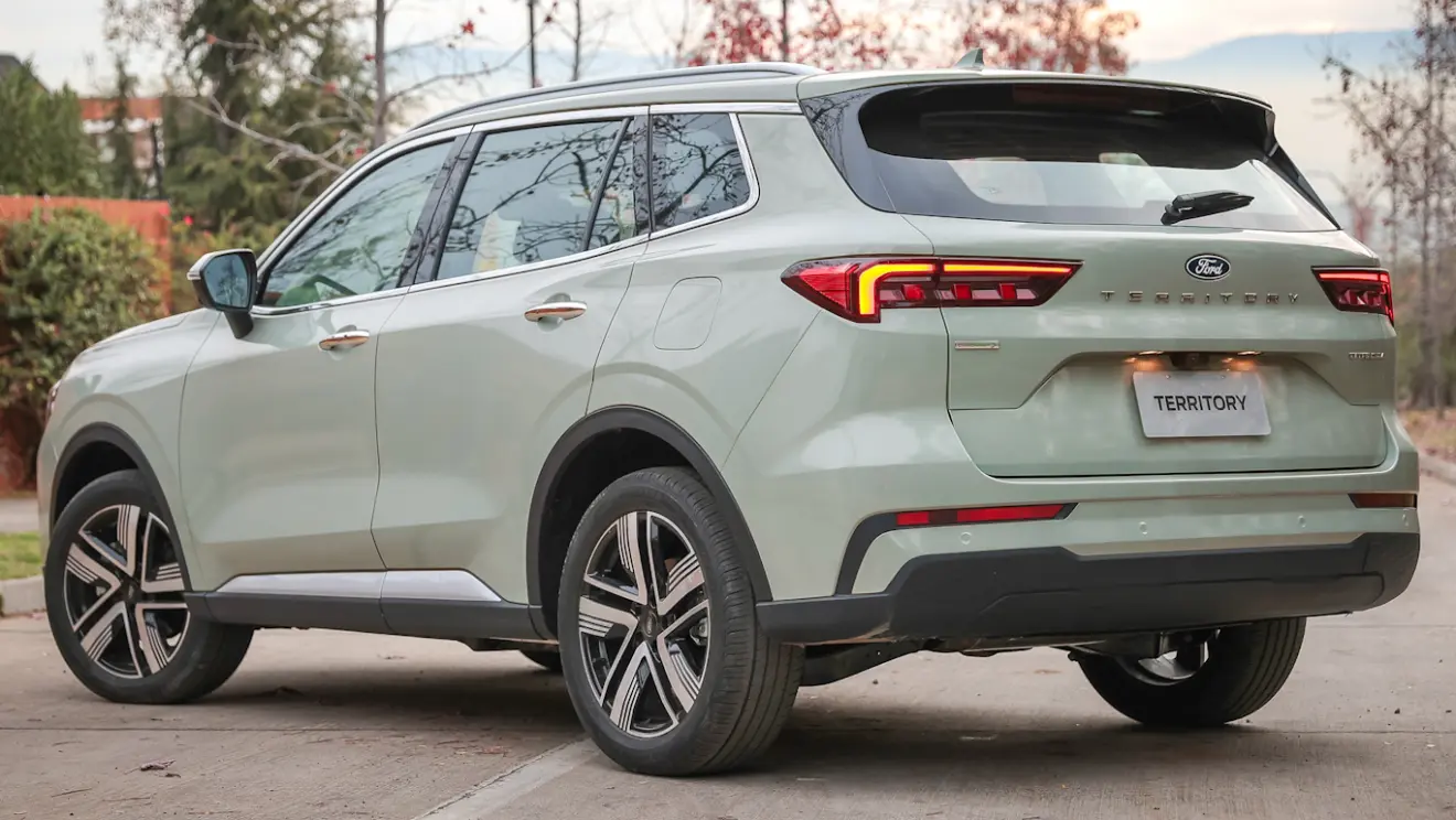 Ford Territory reestilizado cinza claro, visto de trás e com lanternas acesas
