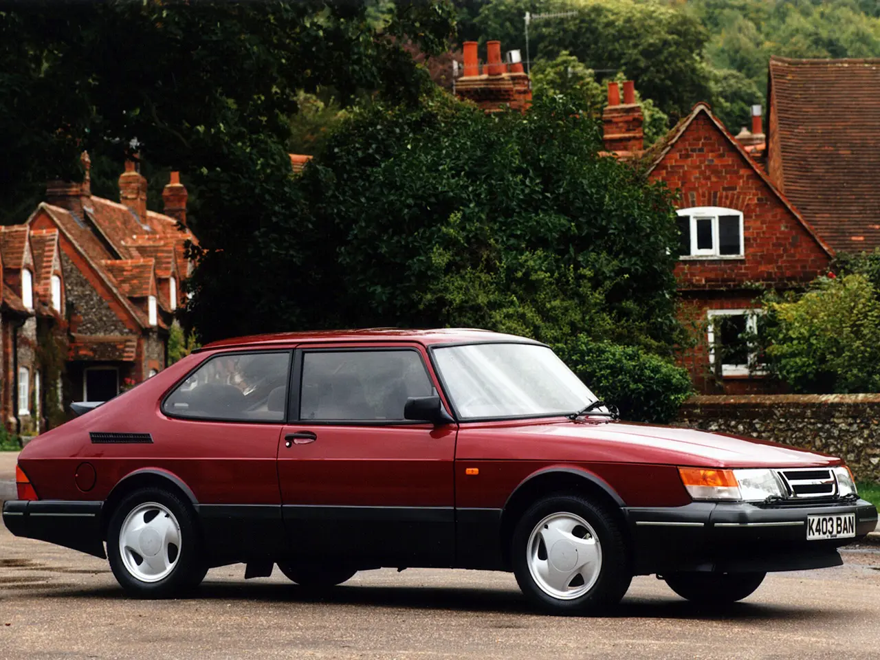 Saab 900 vermelho parado com casa do fundo