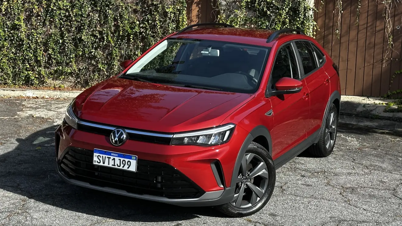 Volkswagen Nivus Comfortline 200TSI vermelho parado de frente e do alto com muro e plantas ao fundo