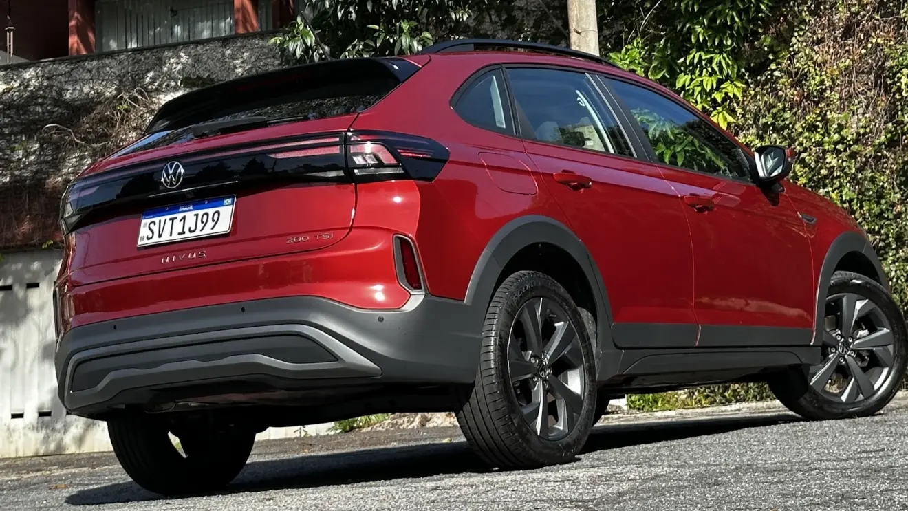 Volkswagen Nivus Comfortline 200TSI vermelho parado de traseira com muro e plantas ao fundo