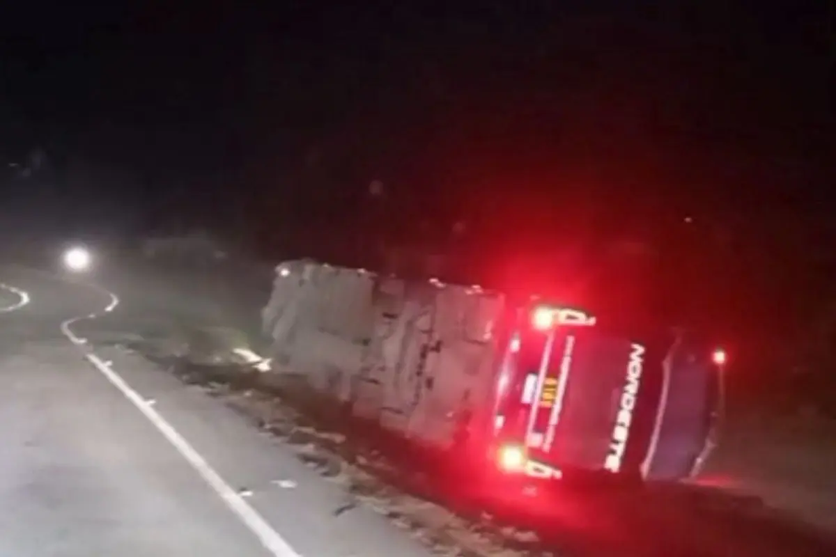 ônibus tombado após acidente e com lanternas acesas