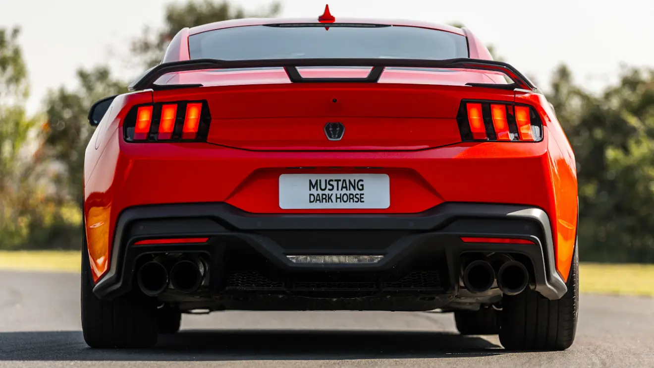 Ford Mustang Dark Horse vermelho visto de trás e com lanternas acesas