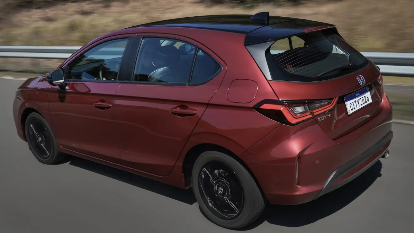 Honda City hatch Touring Sport vermelho, visto de trás e com lanternas acesas