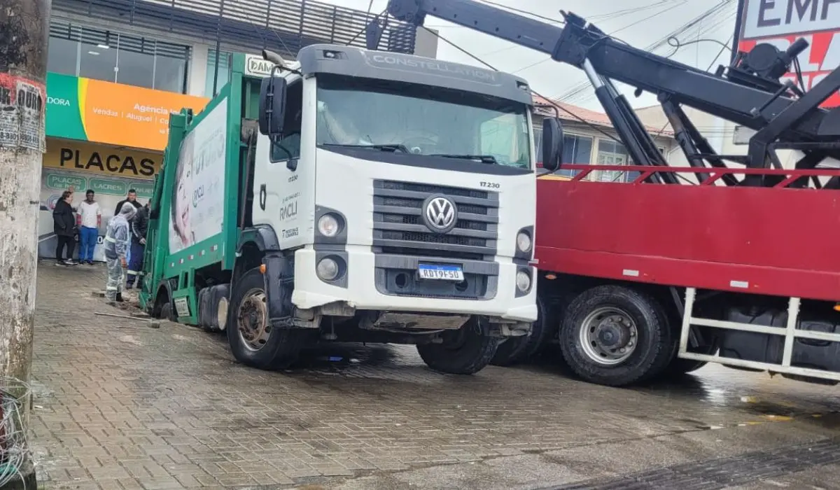 caminhão de lixo branco da Volkswagen parcialmente engolido por calçada
