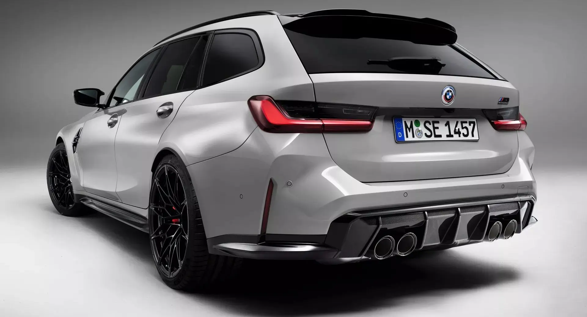 Perua BMW M3 Touring prata parada de frente com fundo neutro