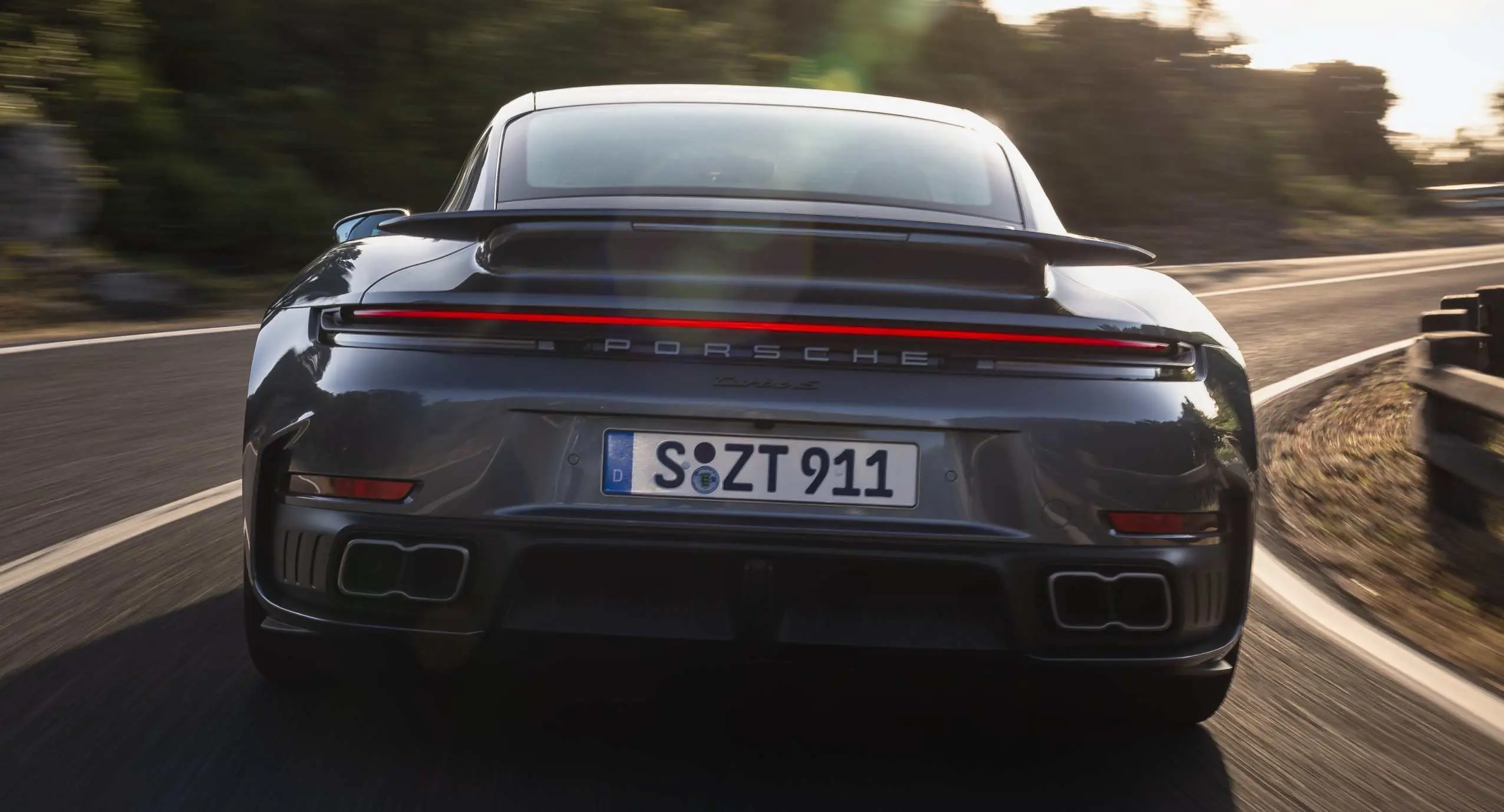 Porsche 911 992.2 Turbo S cinza de traseira em momento na estrada