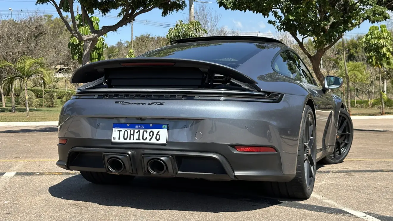 Porsche 911 Carrera GTS cinza parado de traseira com a asa aberta